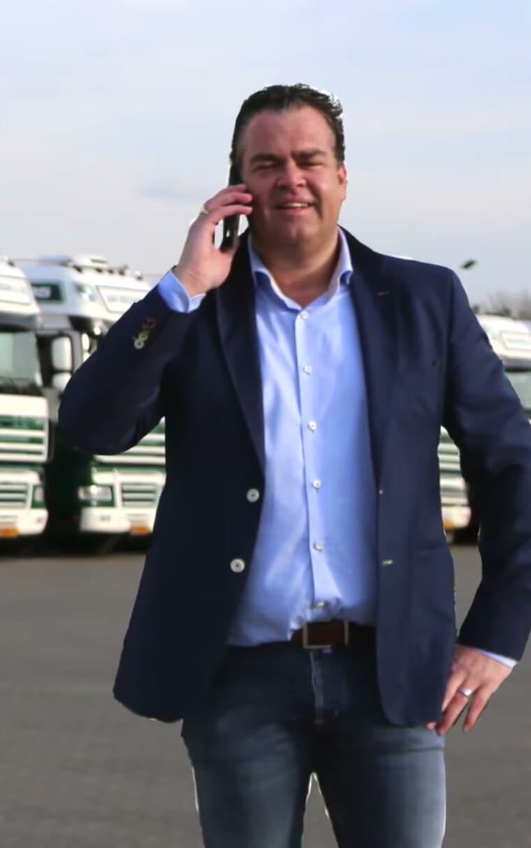 Jan Deckers jr. aan de telefoon, met de vloot op de achtergrond