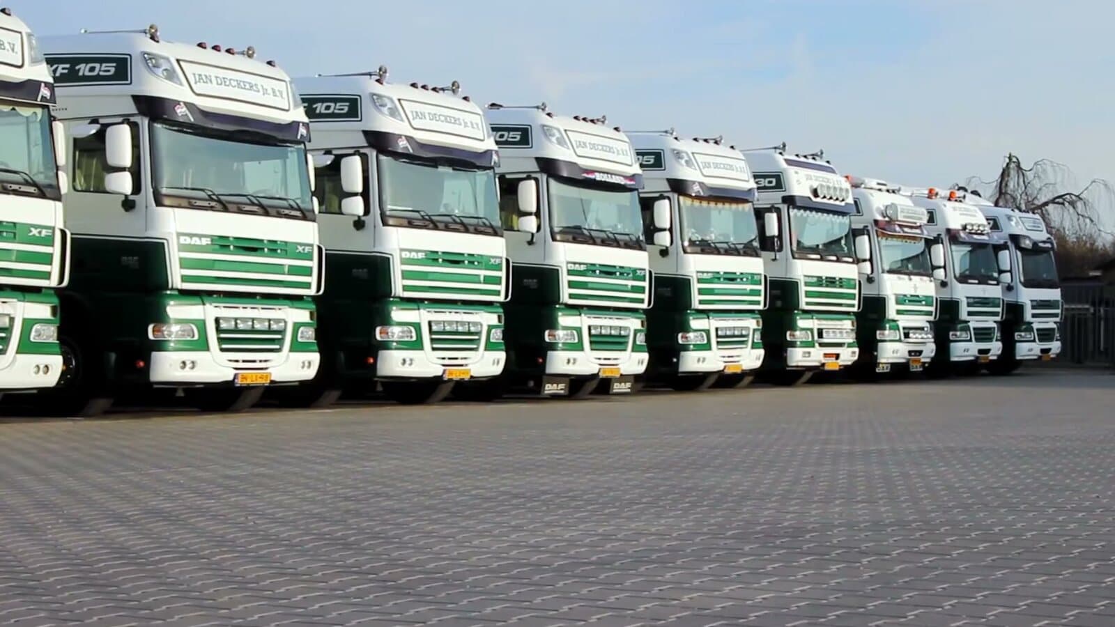 Rij groen-witte trucks van Jan Deckers op het terrein in Ammerzoden